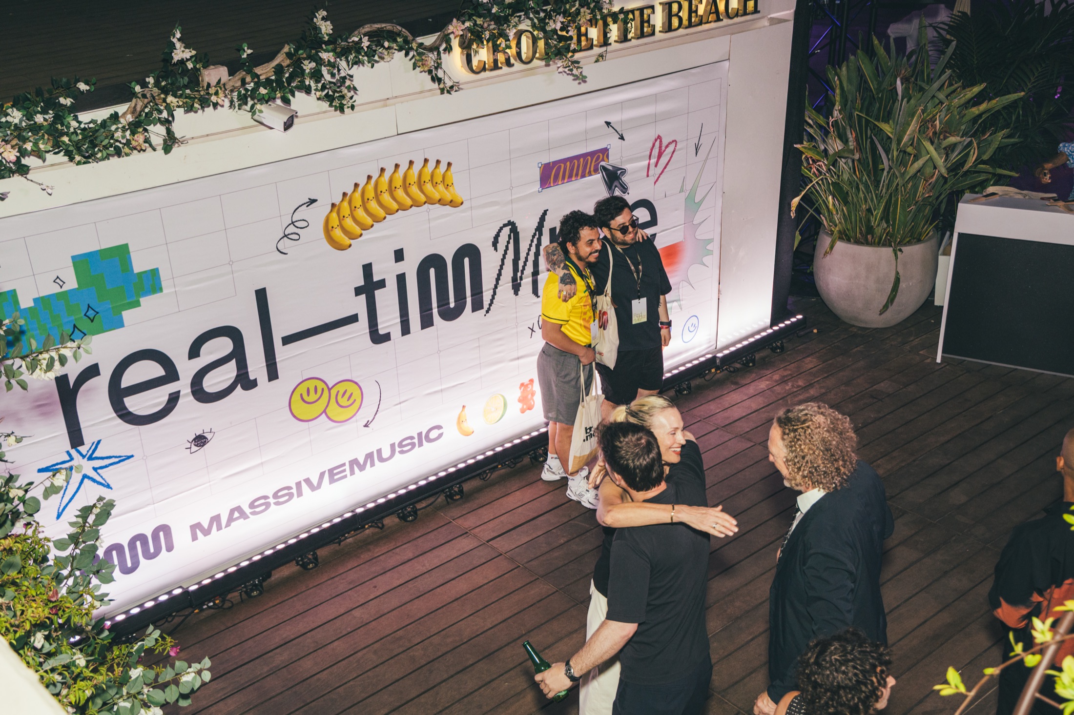 Guests hugging in front of the real-timmme branded wall on Croisette Beach