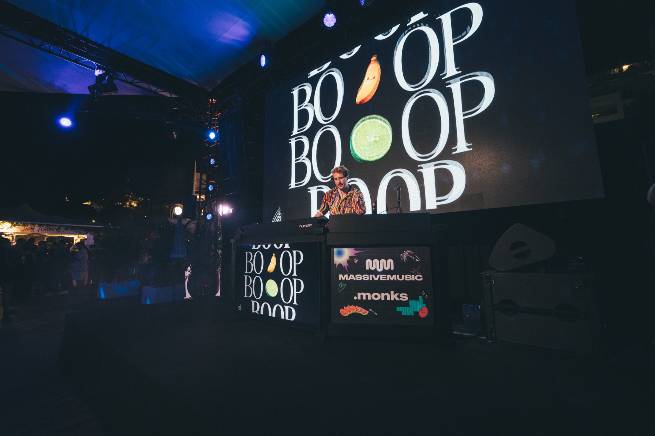 DJ performing in front of a large screen displaying the BOOP key visual at the MassiveMusic x Monks Cannes Lions party