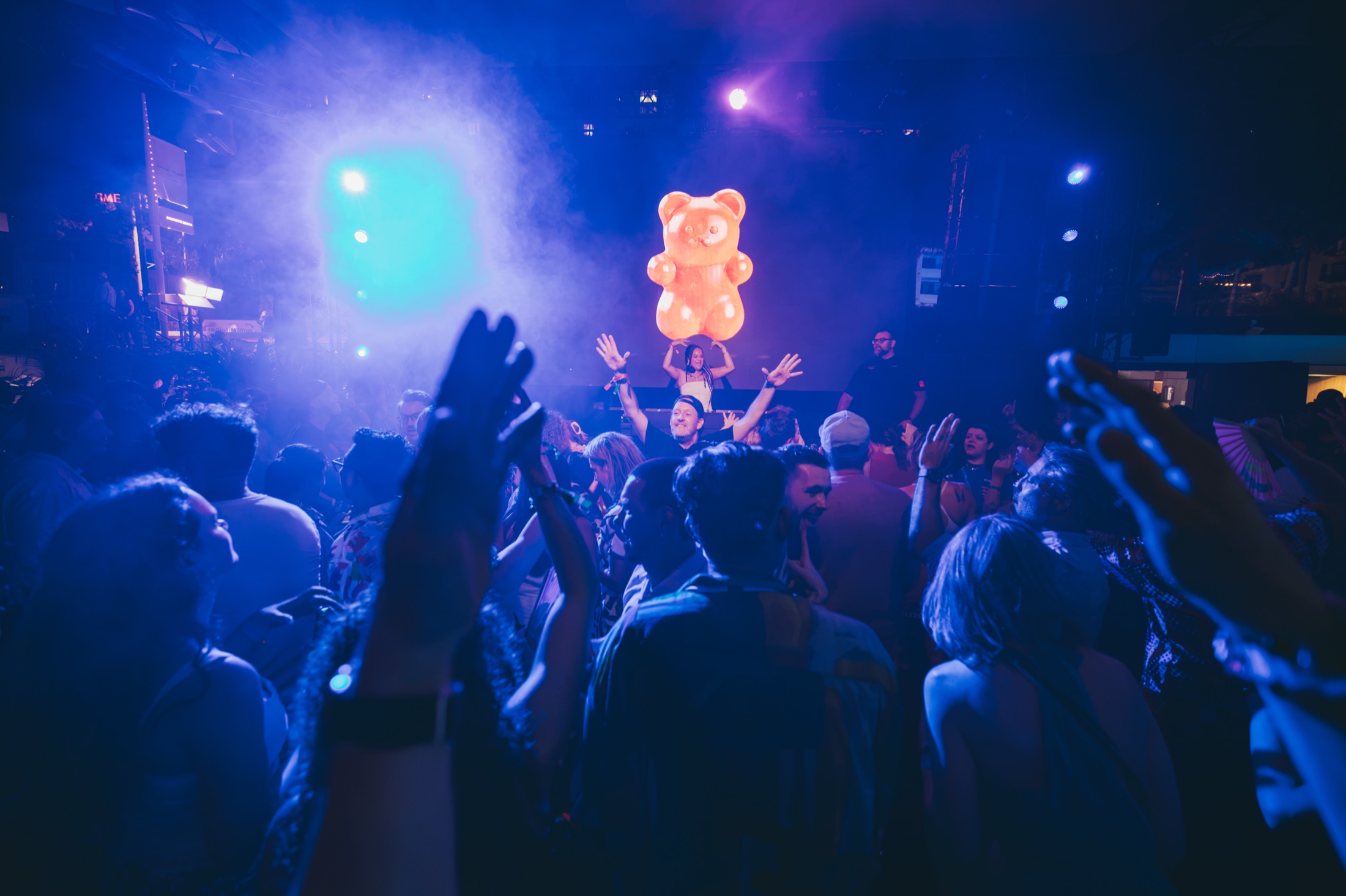 Crowd dancing under a giant inflatable gummy bear balloon