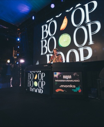 DJ performing in front of the IT'S REAL-TIMMME key visual at the MassiveMusic x Monks Cannes Lions party